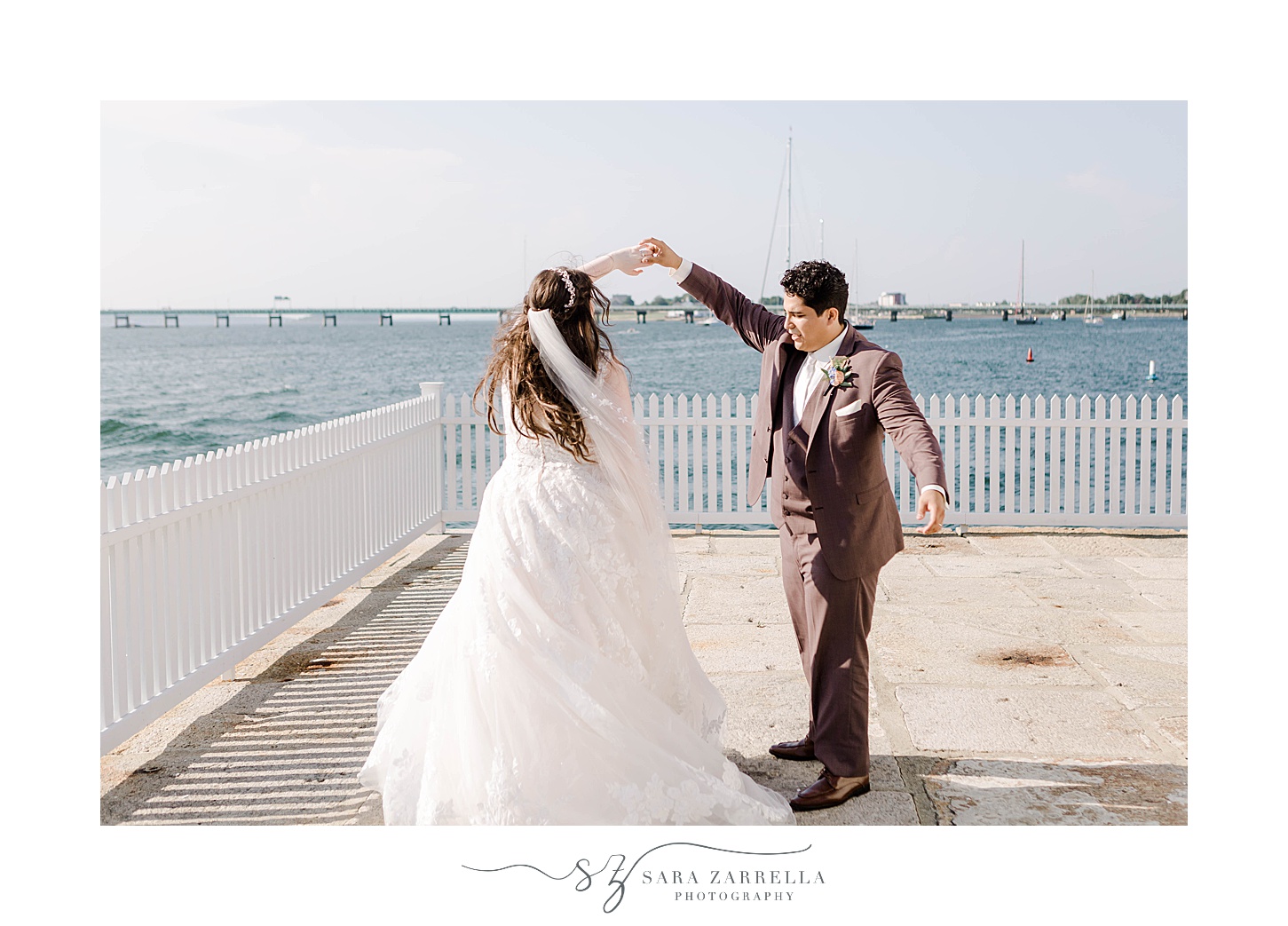 groom twirls bride by white fence at Newport Harbor Island Resort
