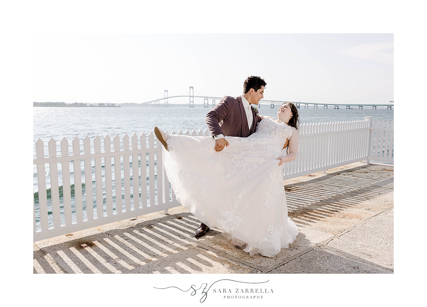 groom dips bride standing beside white fence at Newport Harbor Island Resort