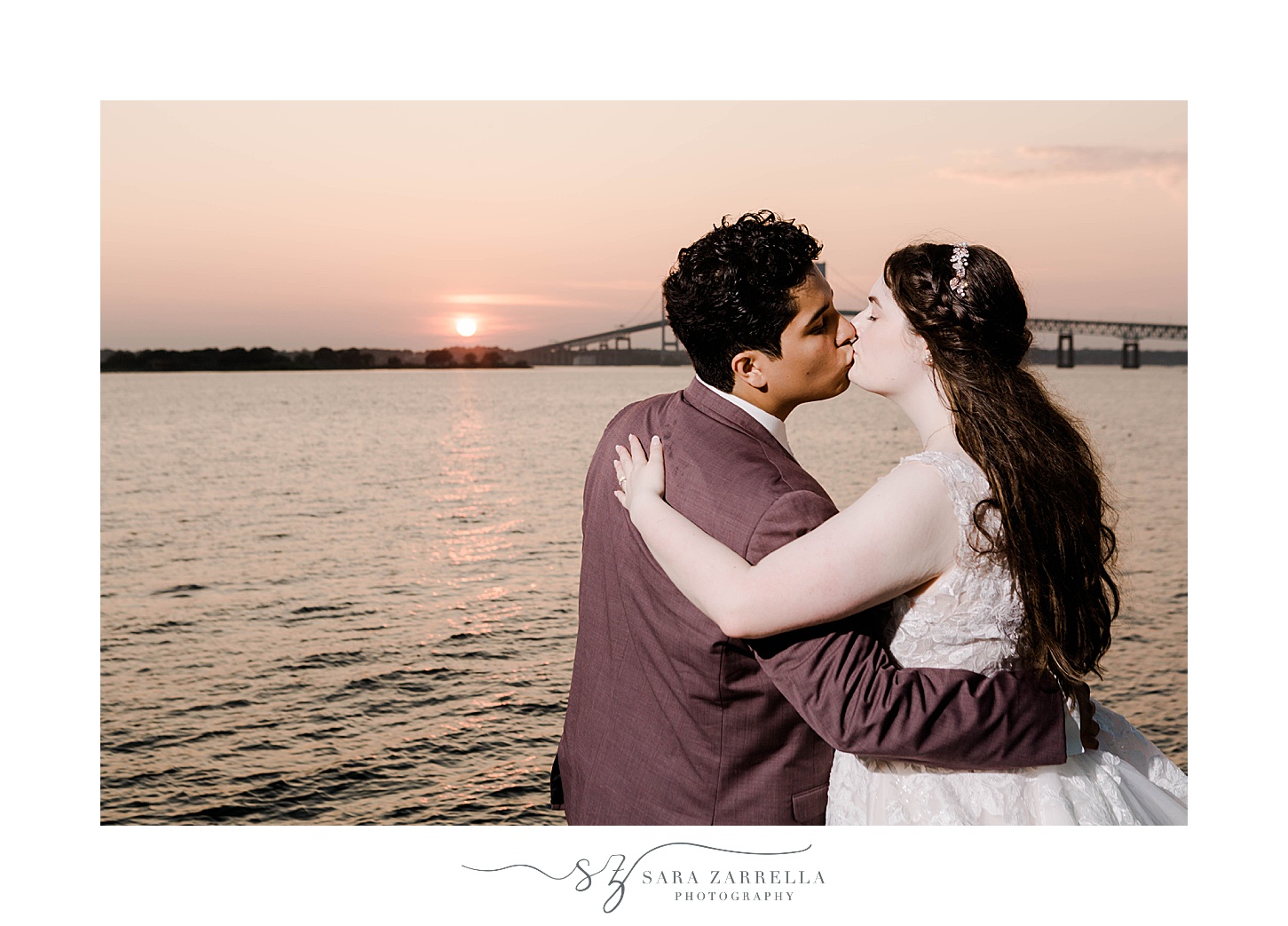 newlyweds kiss at sunset in front of the bay outside Newport Harbor Island Resort