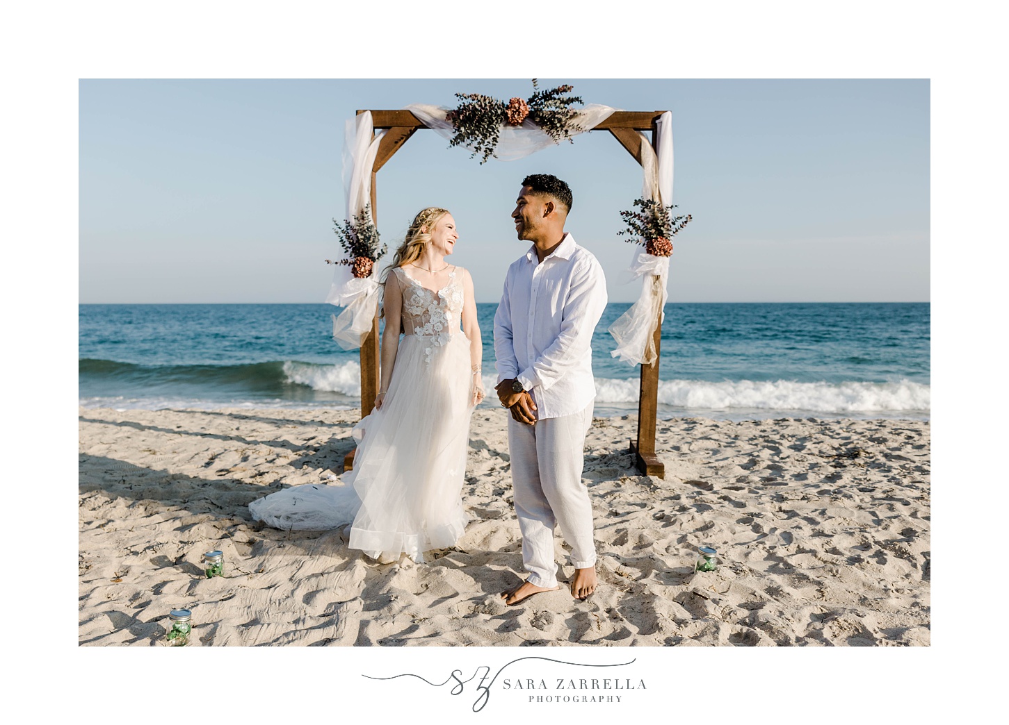 bride and groom stand talking under arbor after Charlestown beach wedding