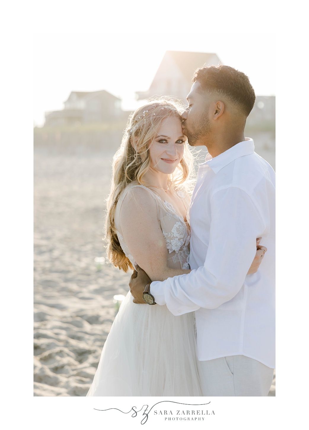 groom hugs bride kissing her forehead at sunset on Charlestown Beach
