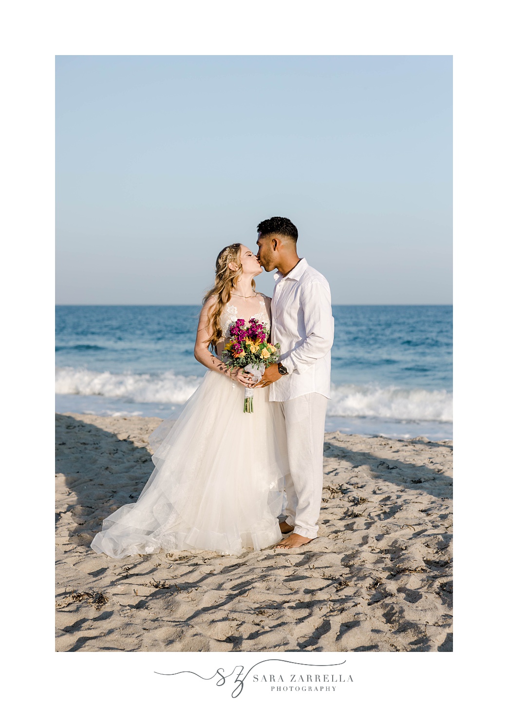 bride and groom kiss on sand of Charlestown Beach