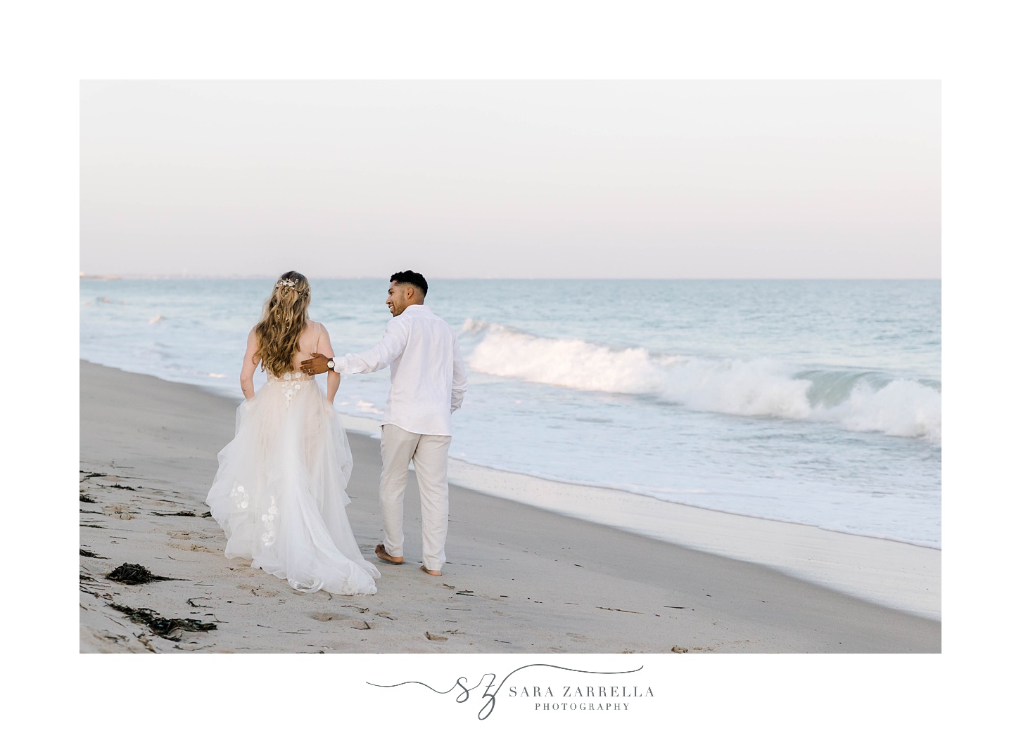 bride and groom hold hands walking beach near ocean
