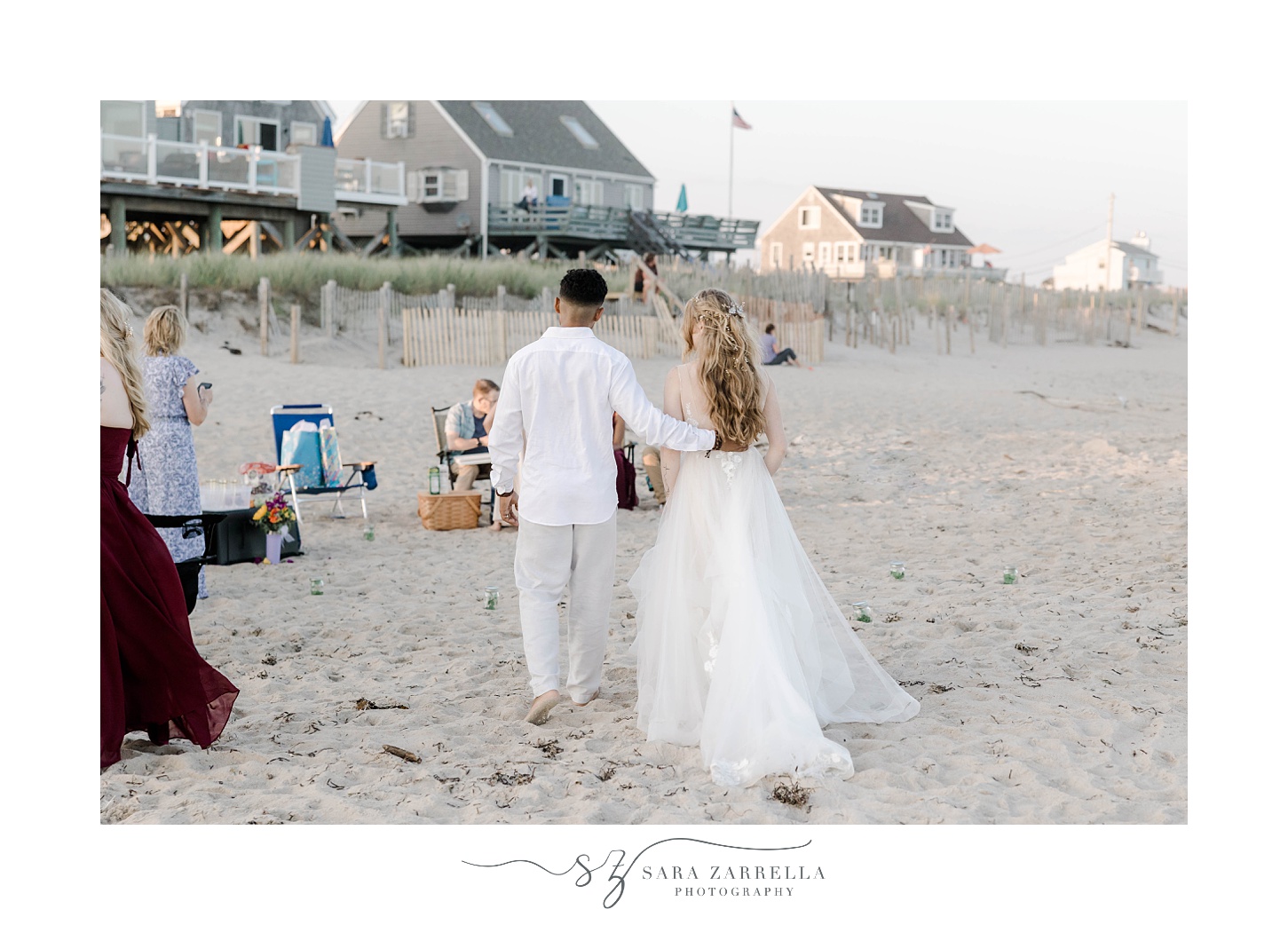 newlyweds walk towards guests on beach after wedding ceremony 