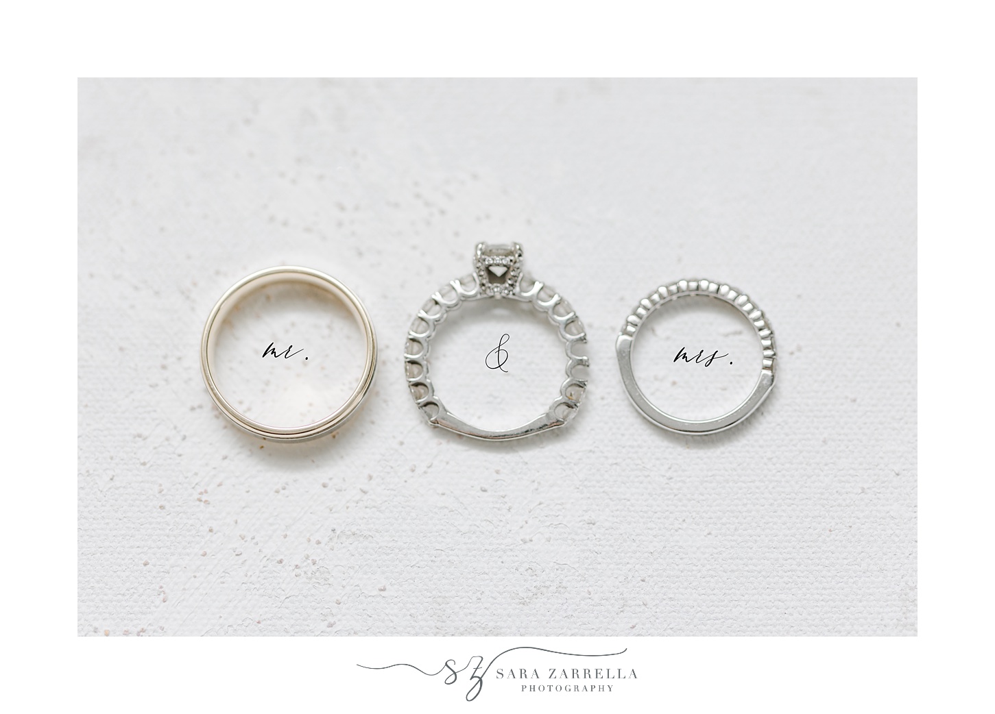 three diamond rings lay on ivory marbled surface with MR and MRS underneath 