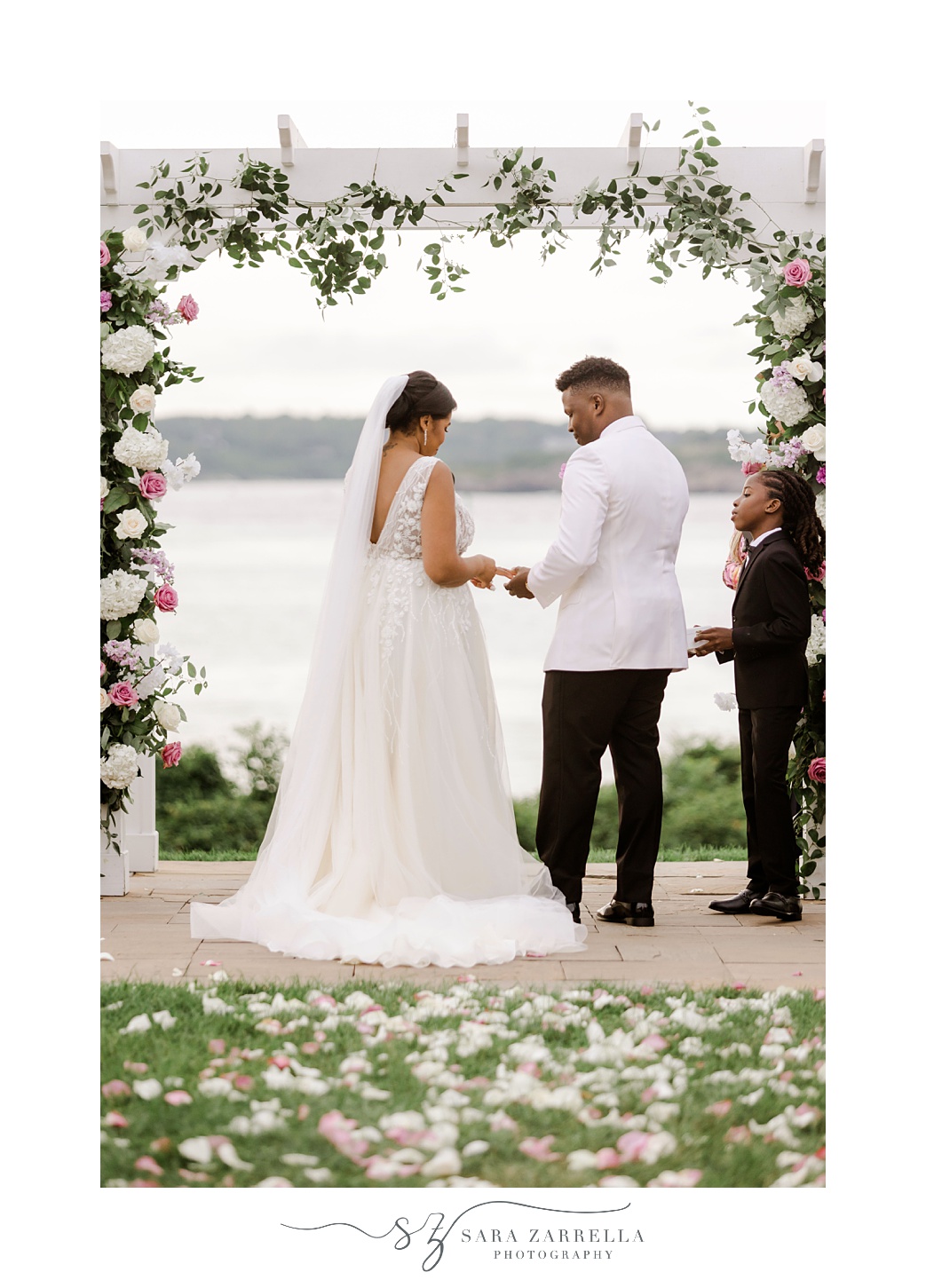 bride and groom exchange vows under floral arbor at OceanCliff Hotel