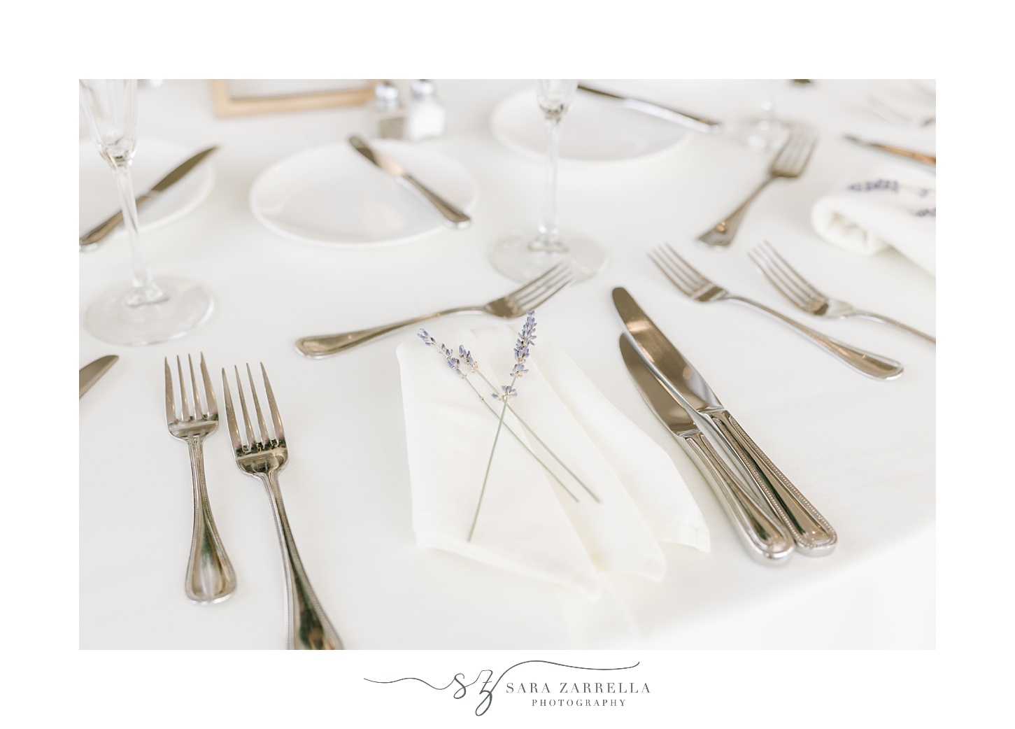 place setting with silverware and white napkins with lavender pieces 