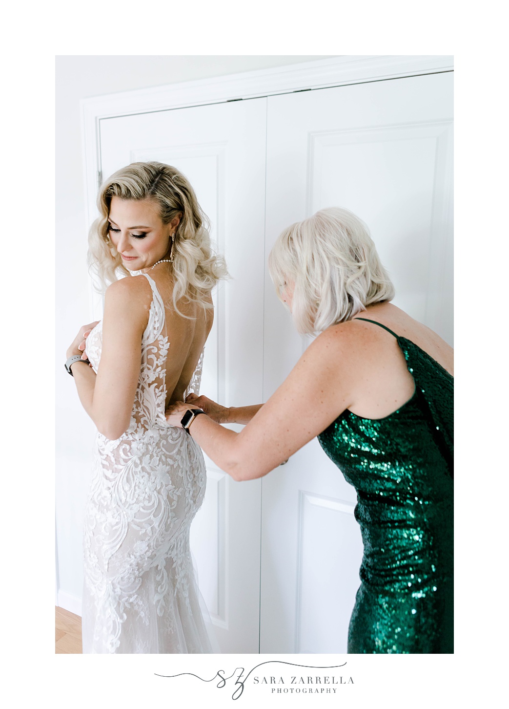 mother in green dress helps bride into wedding dress at Pleasant Valley Country Club