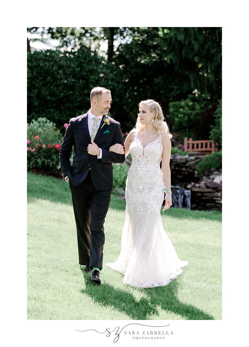 bride and groom link arms walking on lawn at Pleasant Valley Country Club