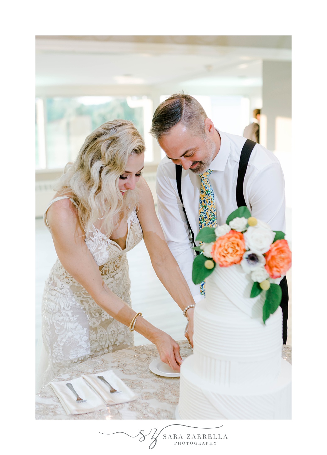 newlyweds cut wedding cake with orange flowers during Sutton MA wedding reception