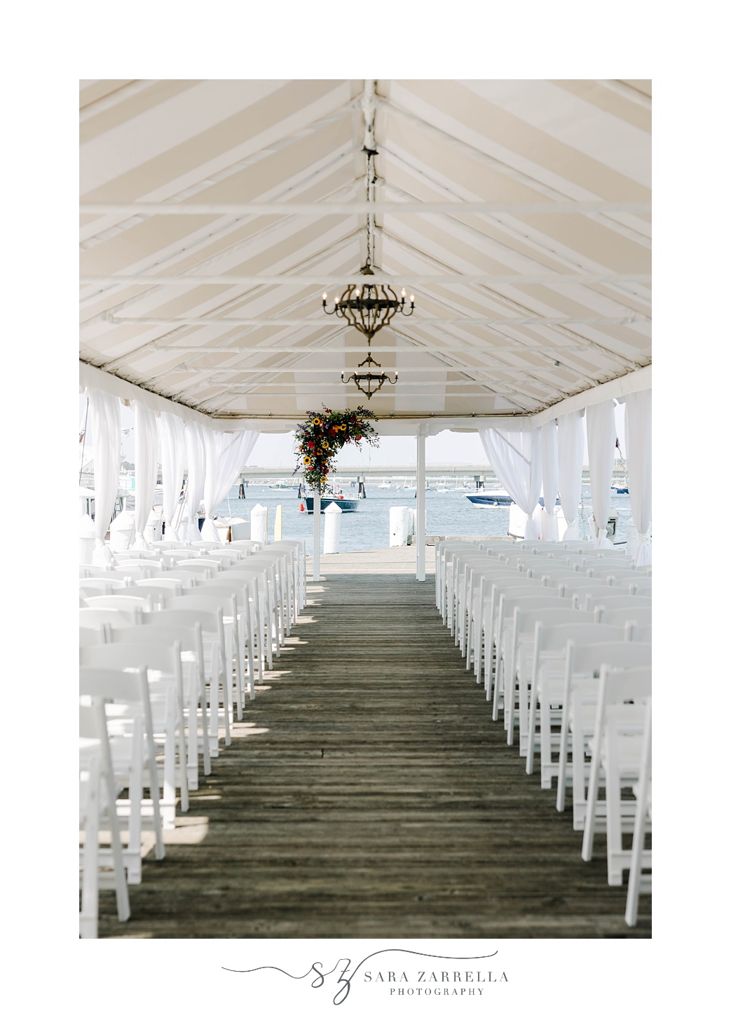 ceremony under tent with white chairs at Regatta Place