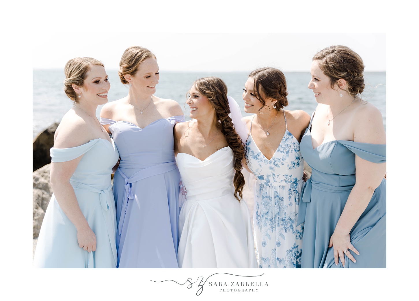 bride hugs bridesmaids in mismatched blue gowns 