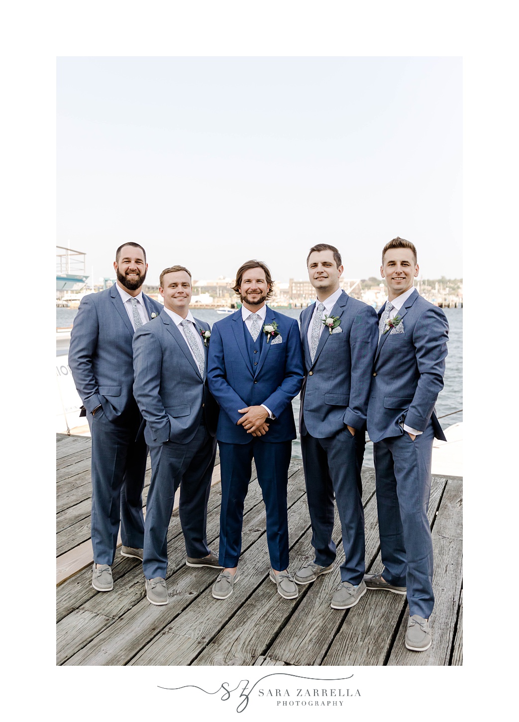 groom stands with groomsmen on dock in Newport RI at Regatta Place