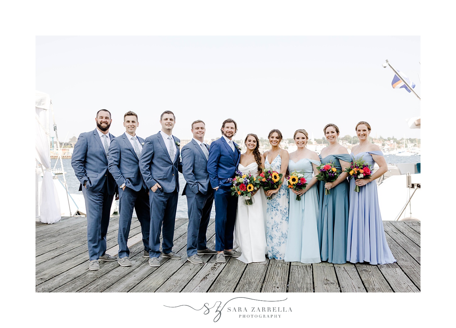 bride and groom stand with wedding party with blue suit and light blue dresses 