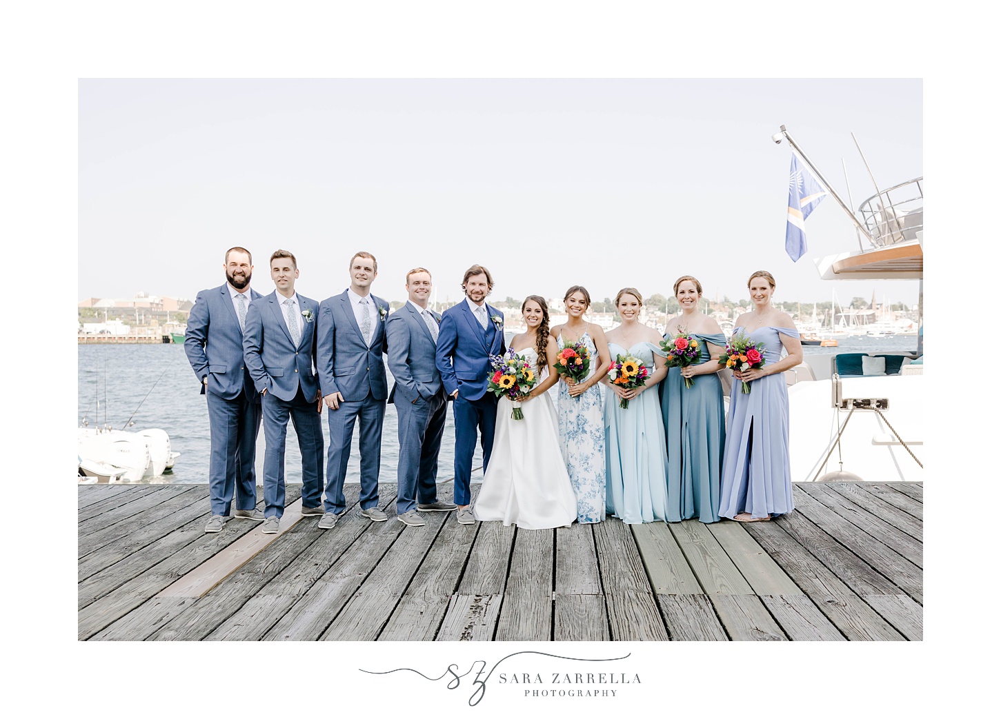 newlyweds stand with wedding party on docks at Regatta Place