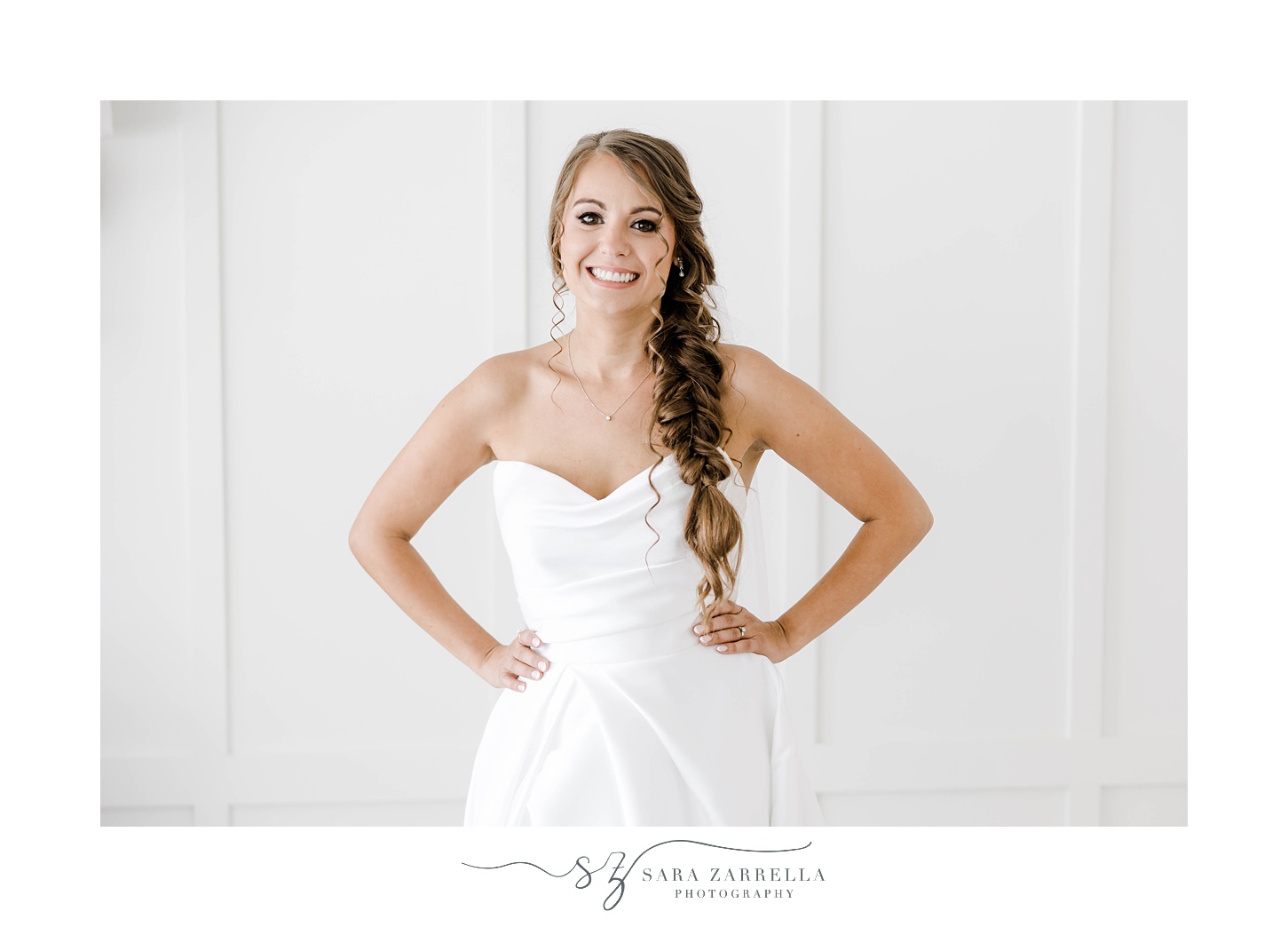 bride in strapless gown stands with hands on hips with fishtail braid 