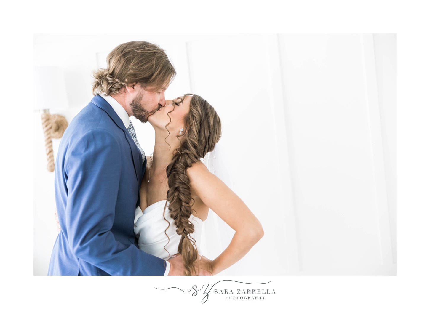 bride and groom kiss in front white wall at Regatta Place