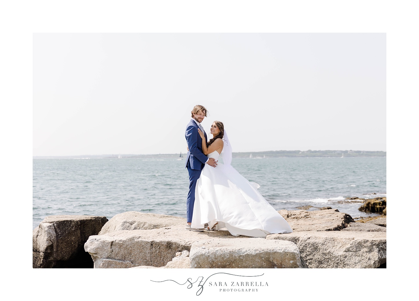 bride and groom hug standing on rocks in Newport RI