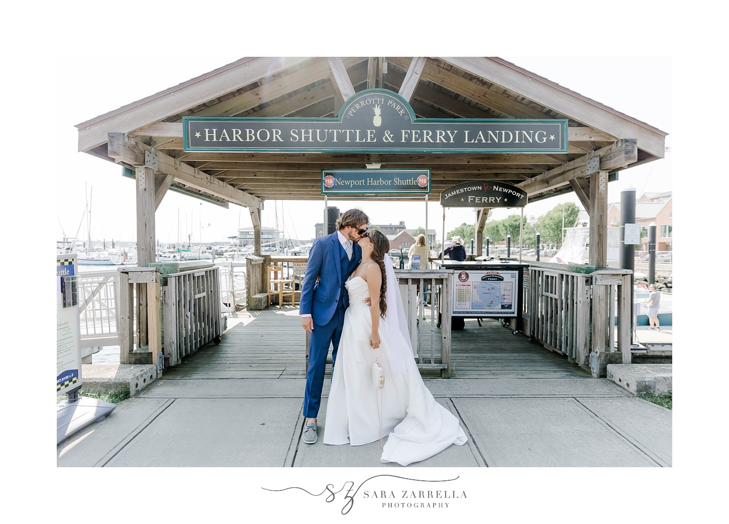 bride and groom kiss under sign at docks in Newport RI
