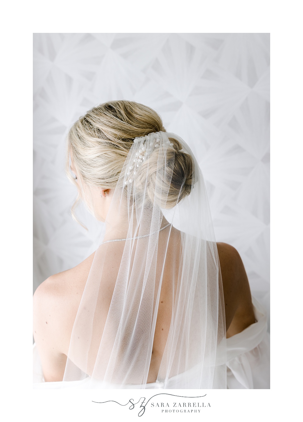 bride looks over shoulder showing off bun and veil draped behind her