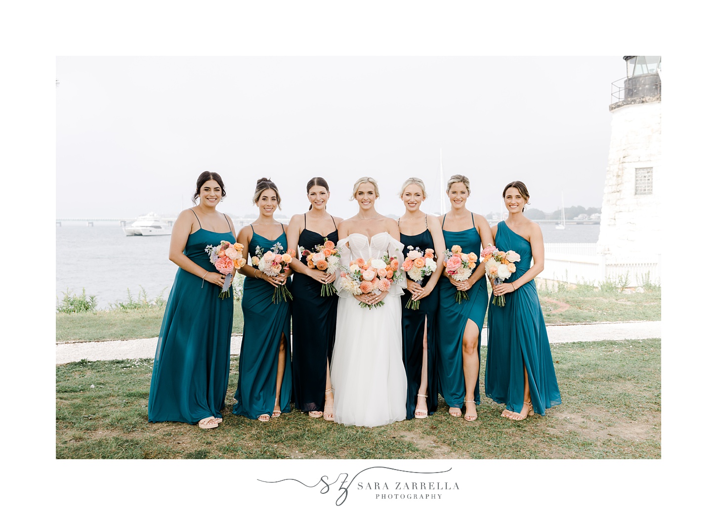 bride poses with bridesmaids in teal gowns in front of Narragansett Bay
