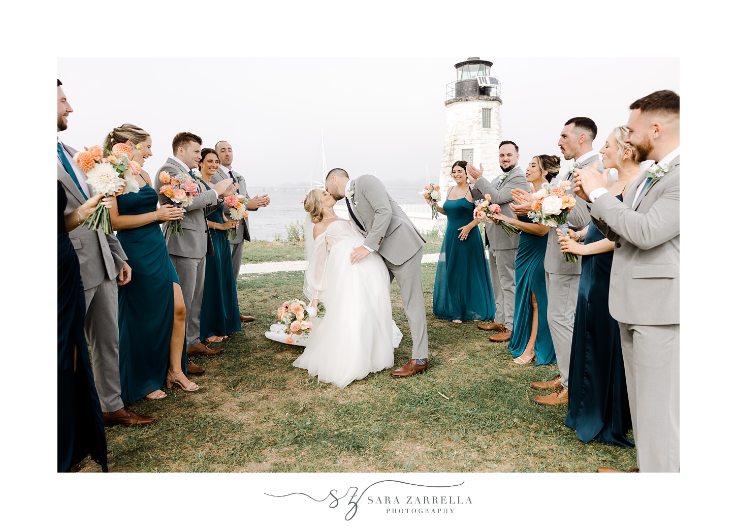 bride and groom kiss at Newport Lighthouse with wedding party clapping around them 