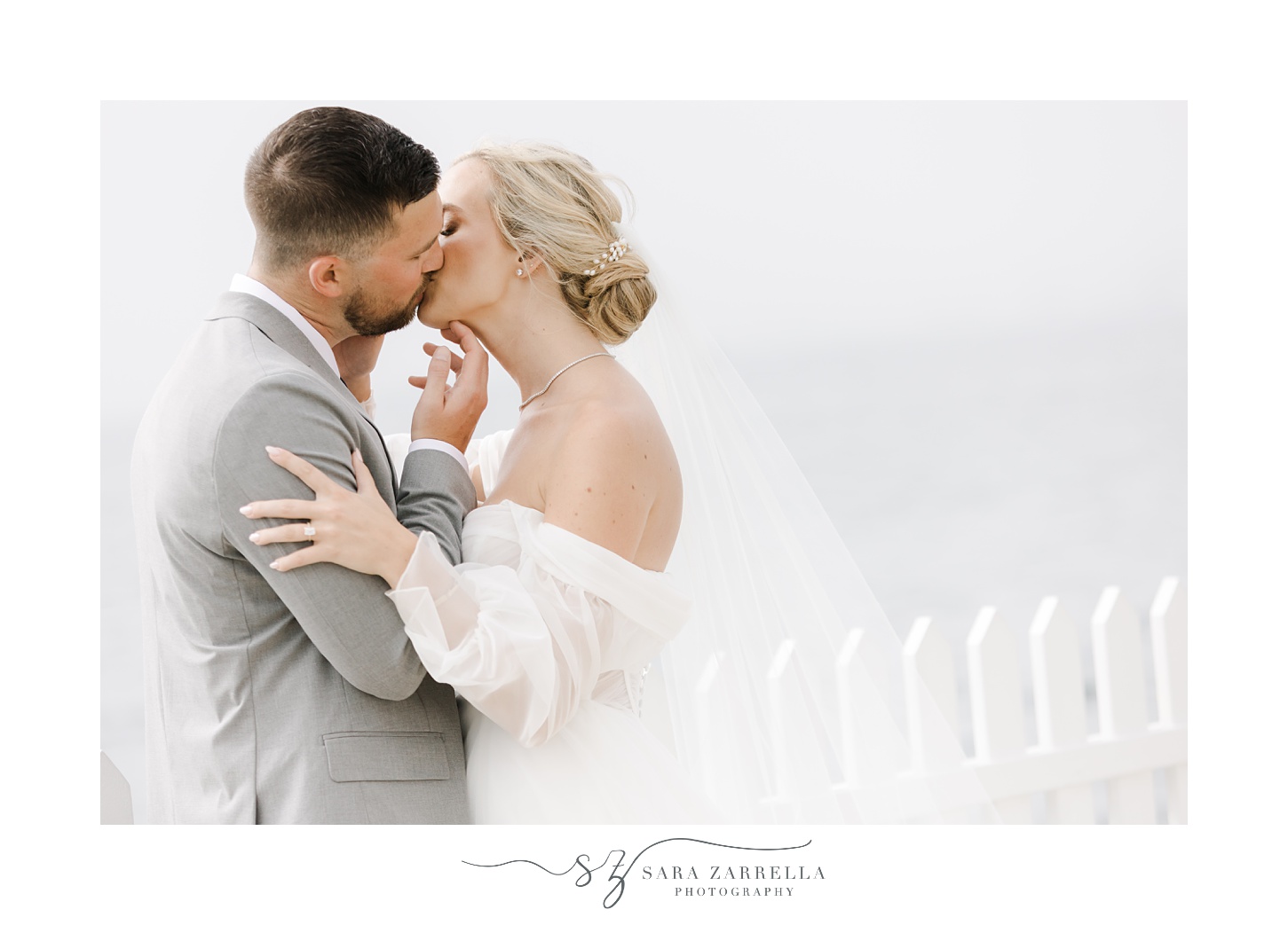 bride and groom lean for a kiss near Narragansett Bay