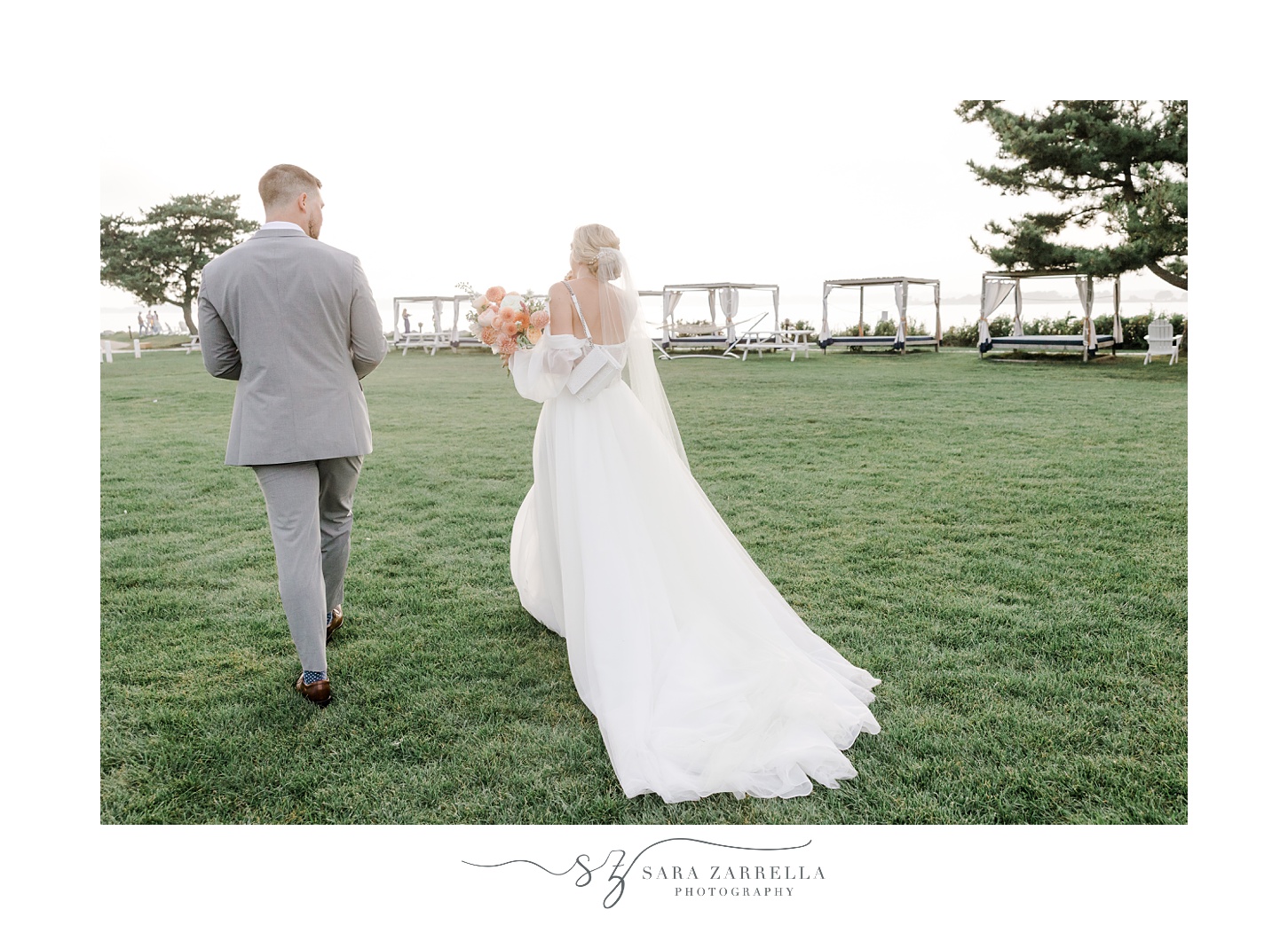 bride and groom walk on lawn towards reception at Newport Harbor Island Resort