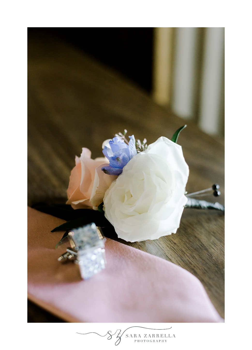 white and pastel peach rose boutonnière for groom with pink tie