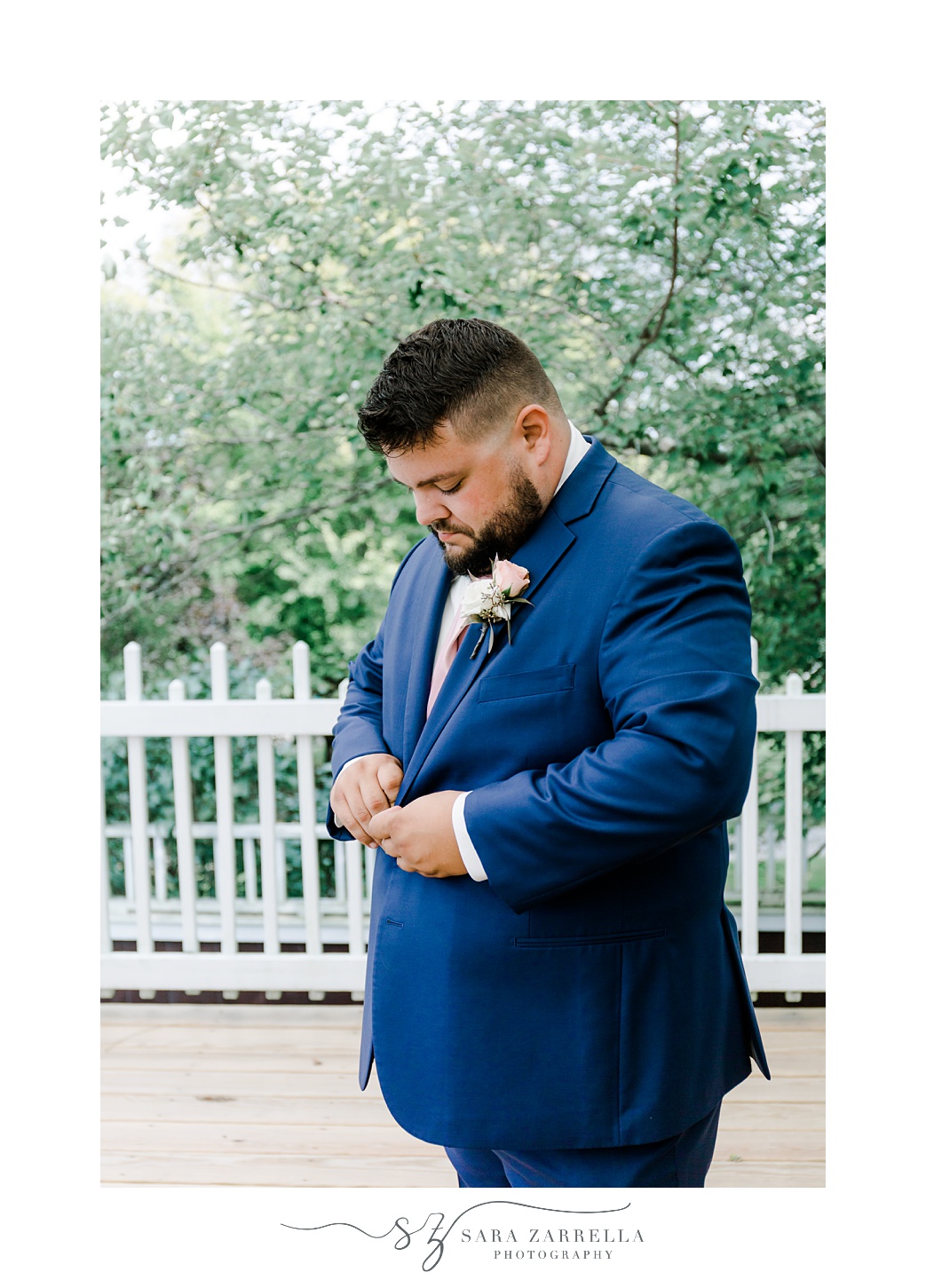 groom adjusts jacket of navy suit before Blissful Meadows wedding 