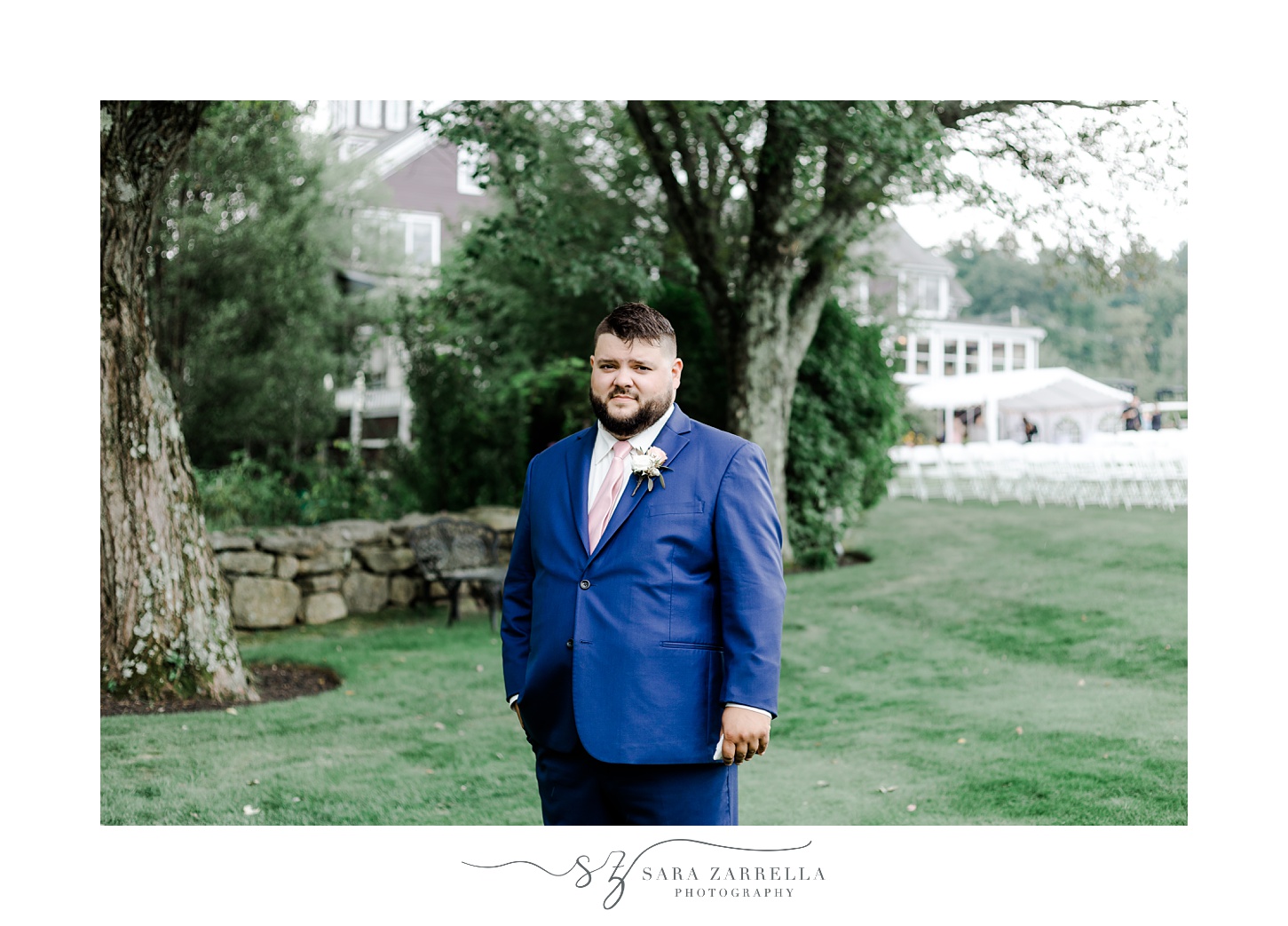groom stands on lawn in navy suit at Blissful Meadows