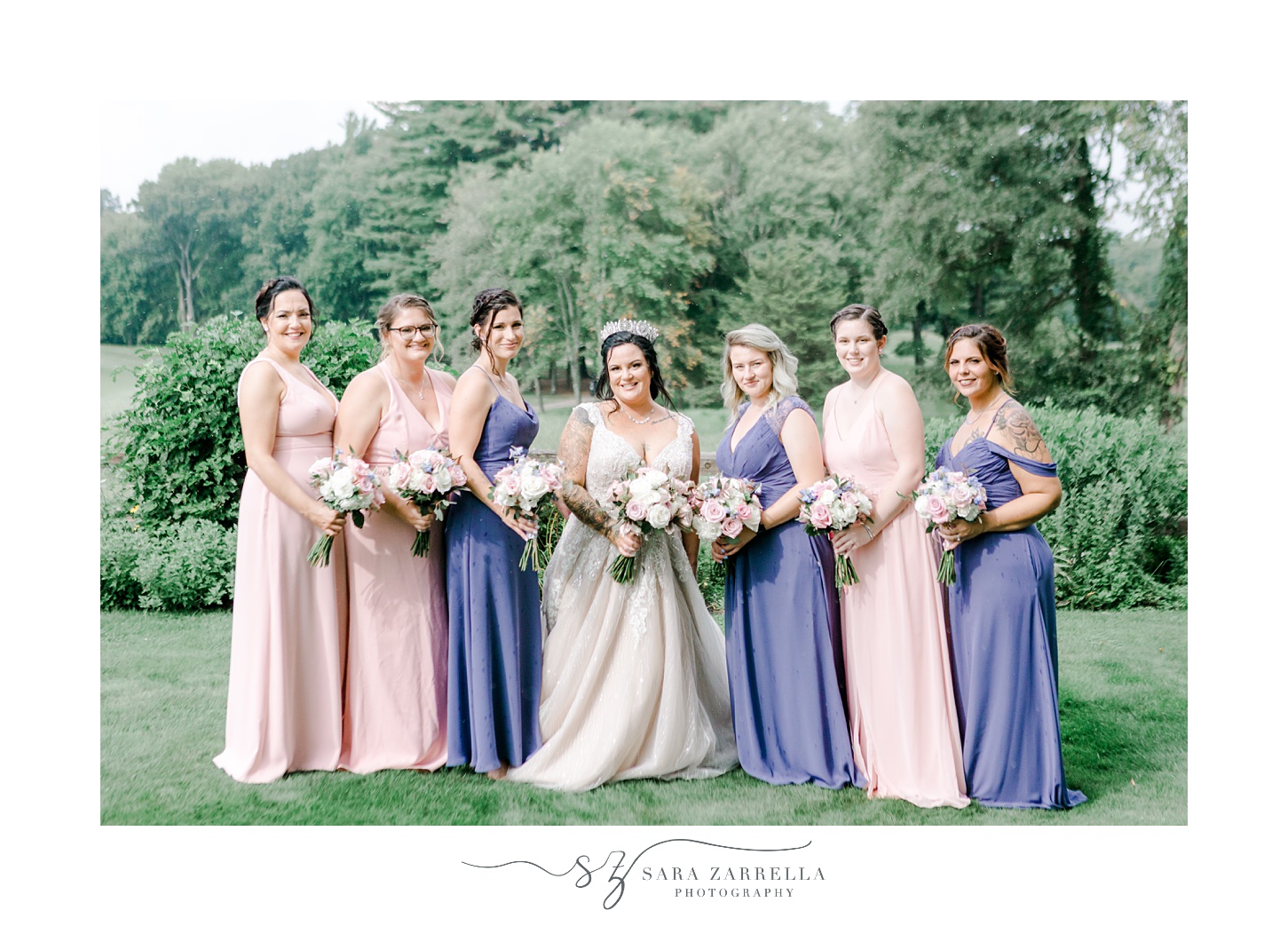 bridesmaids in pink and purple bridesmaid gowns pose with bride at Blissful Meadows