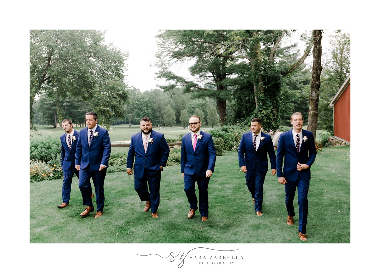 groom walks with groomsmen in navy suits on lawn at Blissful Meadows