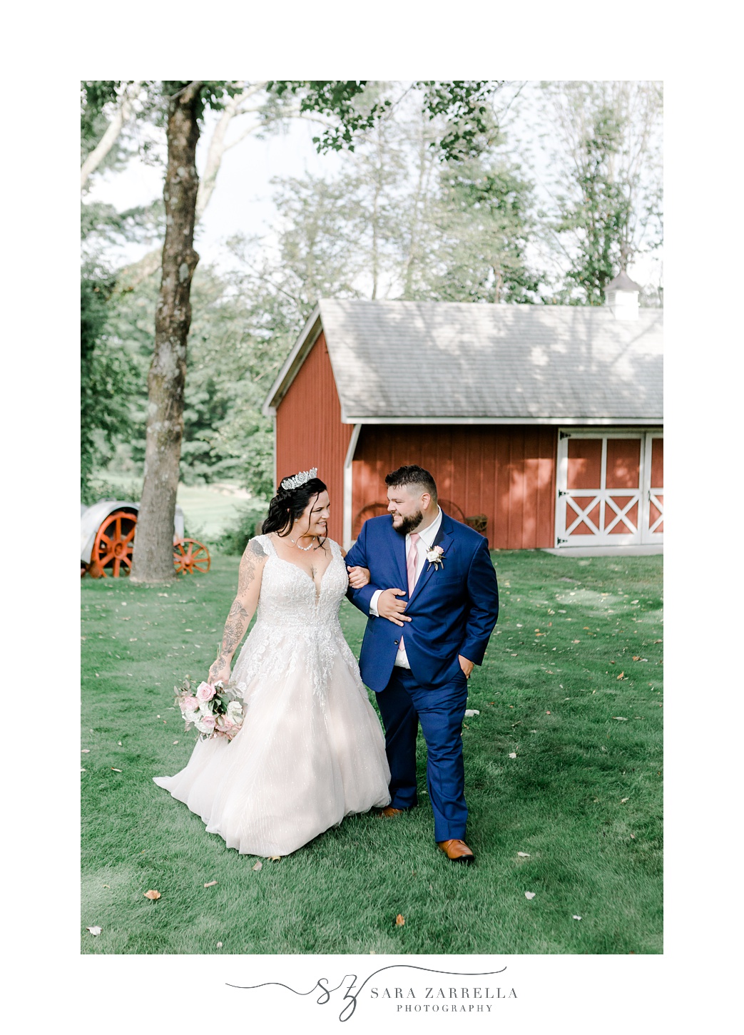 bride and groom hold hands walking in front of red barn during Uxbridge MA wedding day