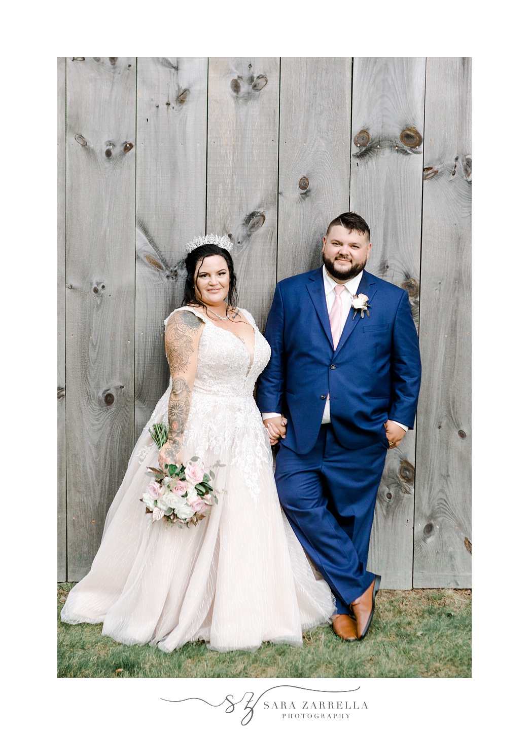 newlyweds lean against wooden barn door