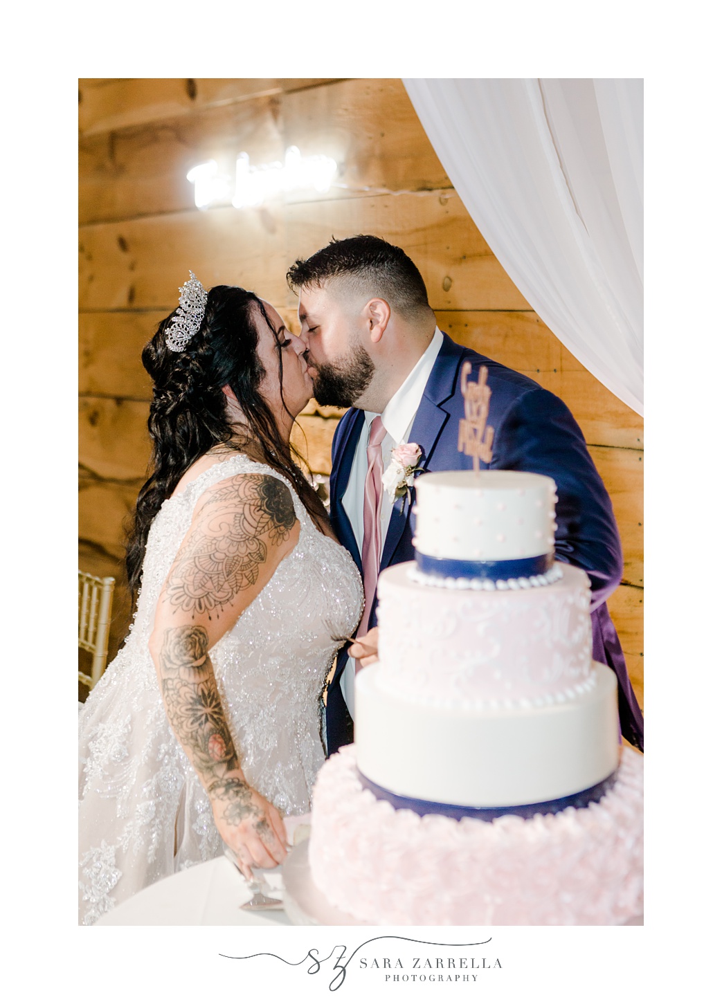 newlyweds cut tiered wedding cake with pink icing and blue ribbons