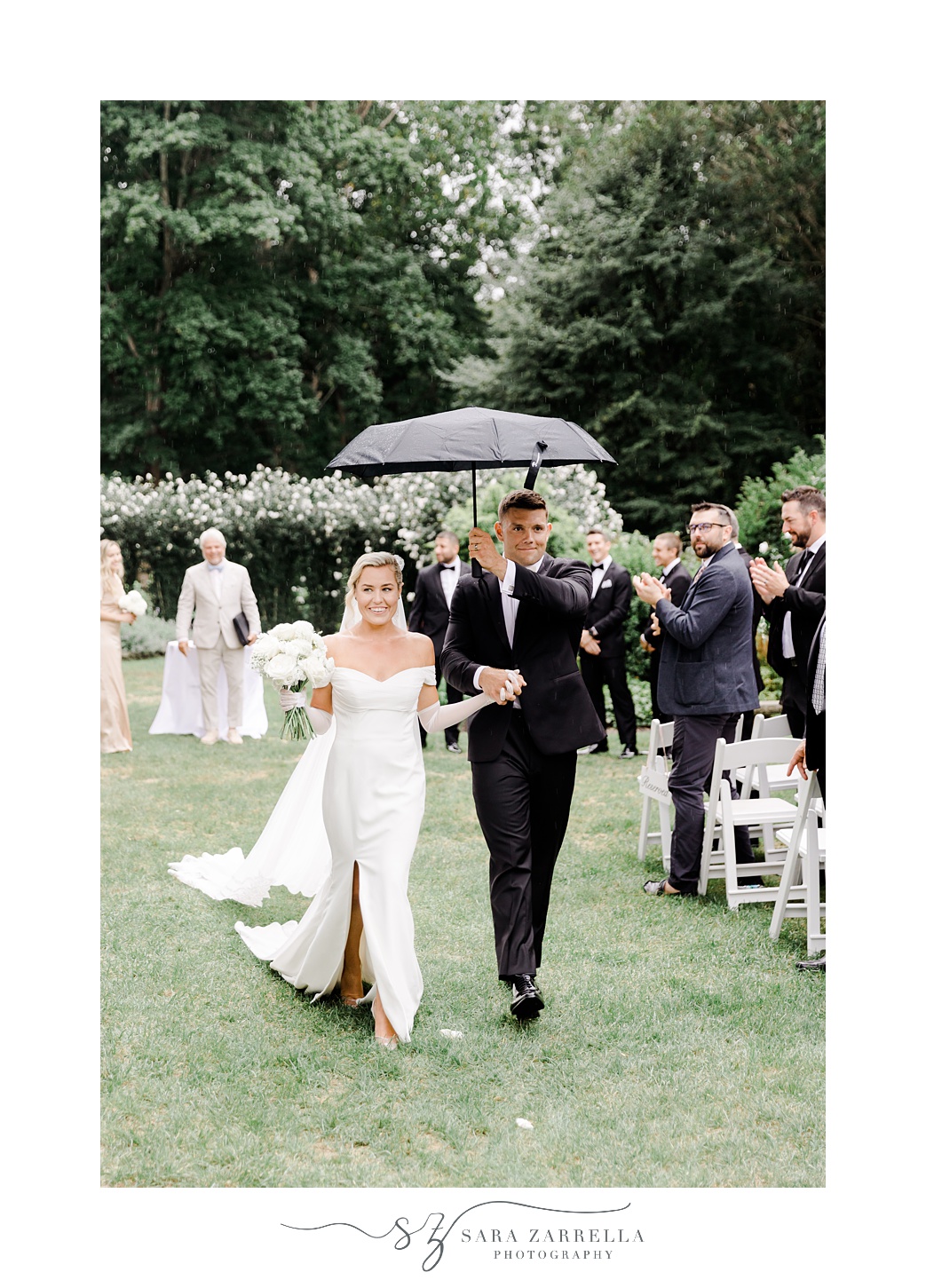 bride and groom recess up aisle under black umbrella at Glen Manor House