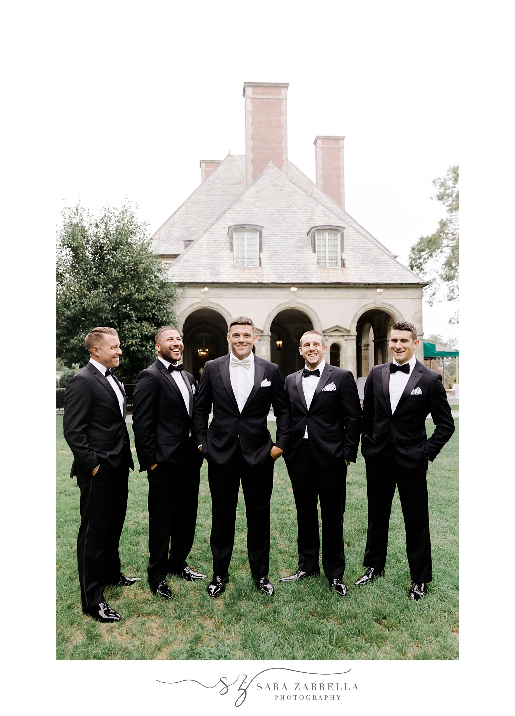 groom and groomsmen pose outside Glen Manor House in black tuxes