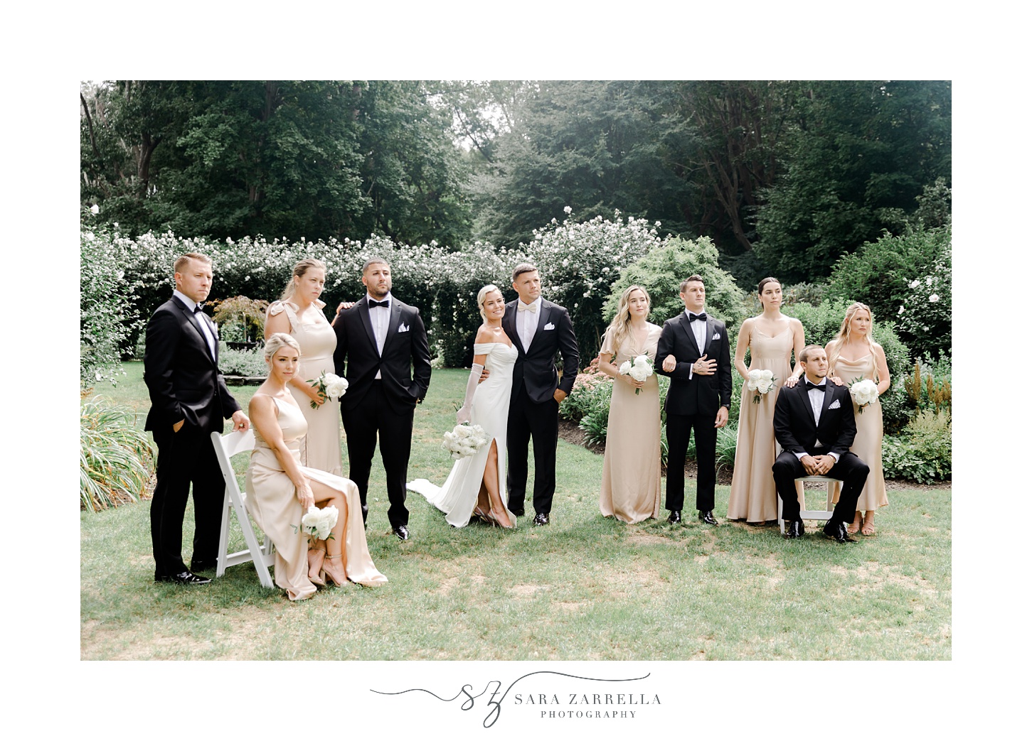 newlyweds stand with wedding party in champagne gowns and black suits 
