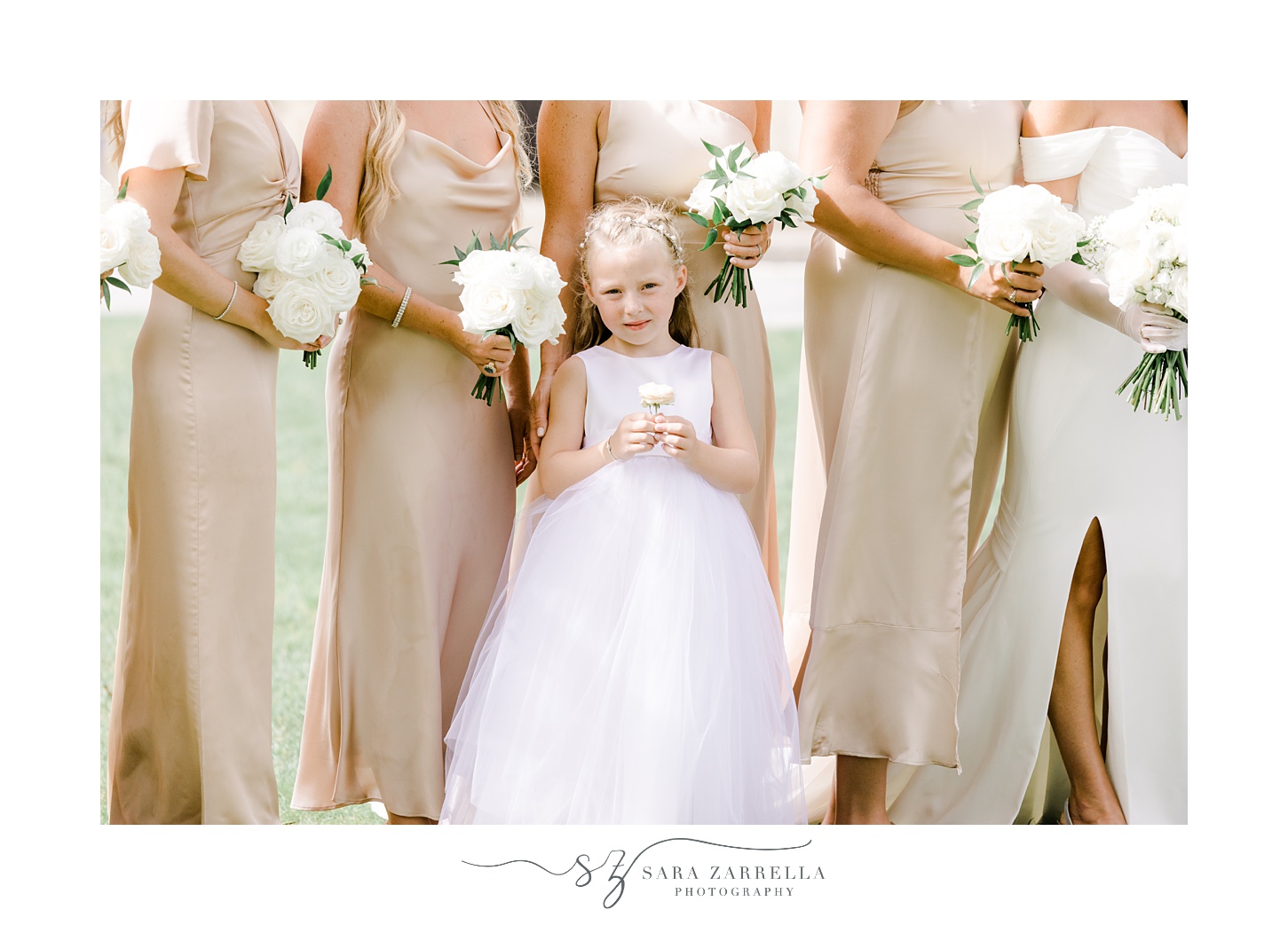 flower girl in white dress stands with bridesmaids in champagne gowns 