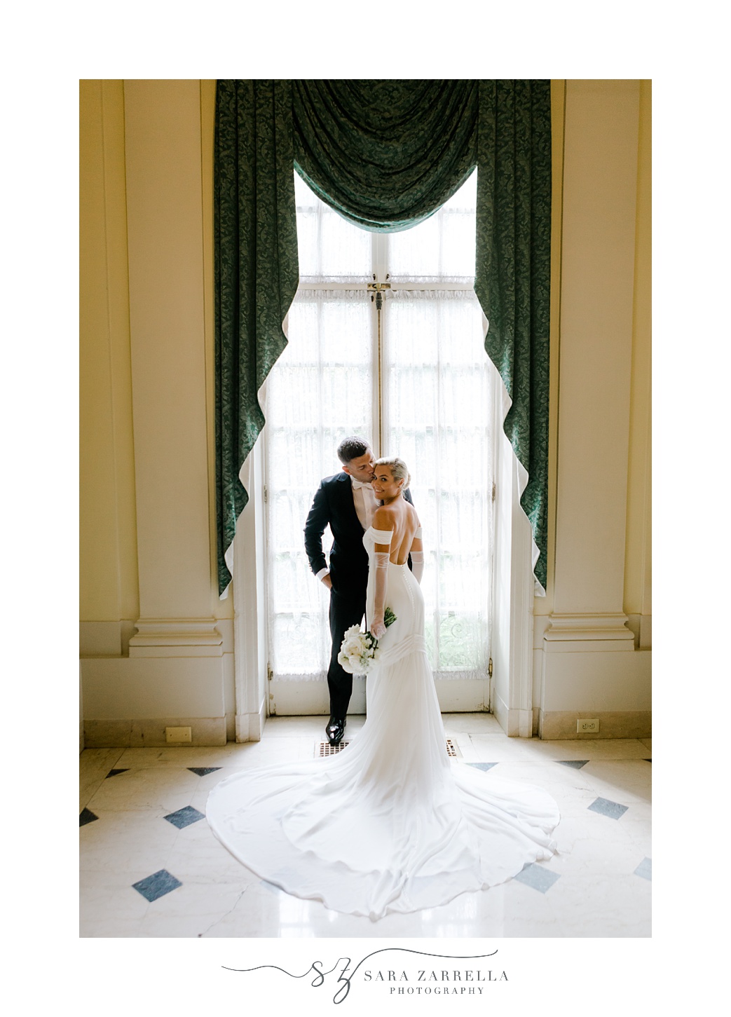 newlyweds hug in window under draped curtain at Glen Manor House