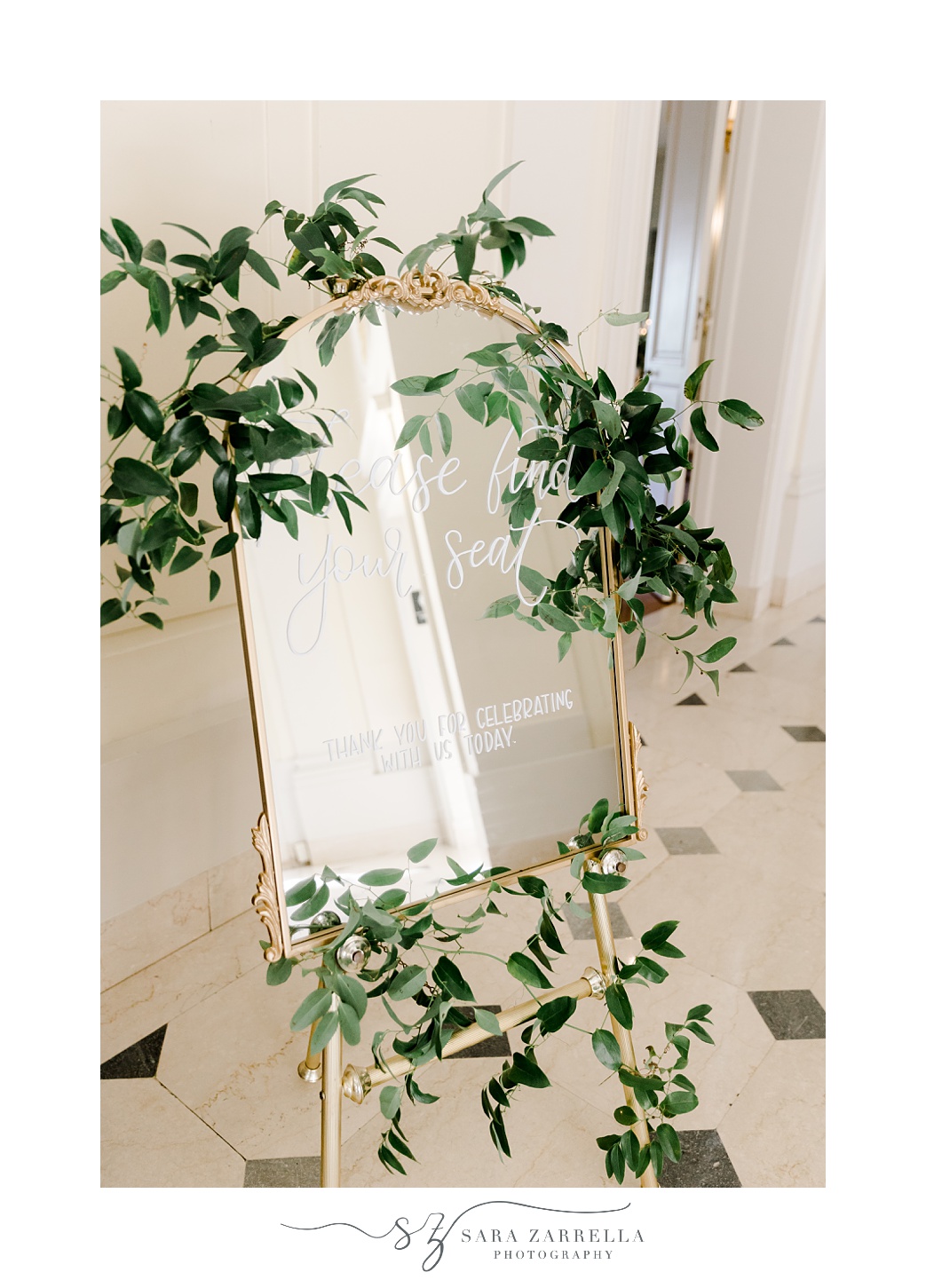 welcome sign on gold framed mirror with greenery around edge 