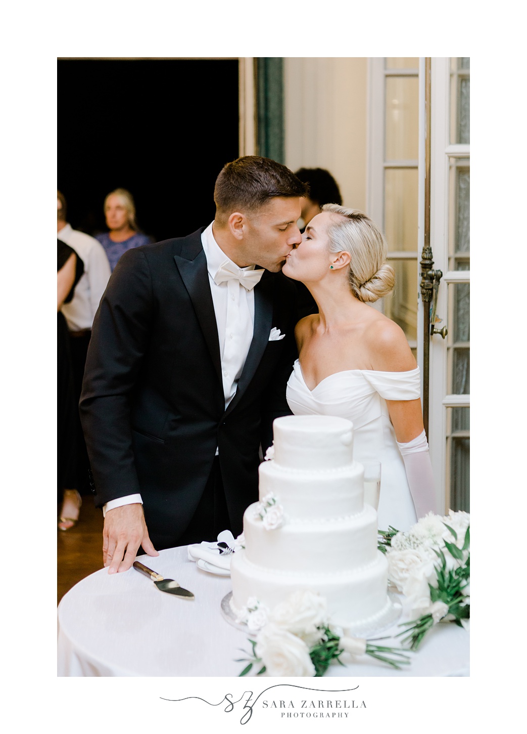 newlyweds kiss by wedding cake during Portsmouth RI wedding reception