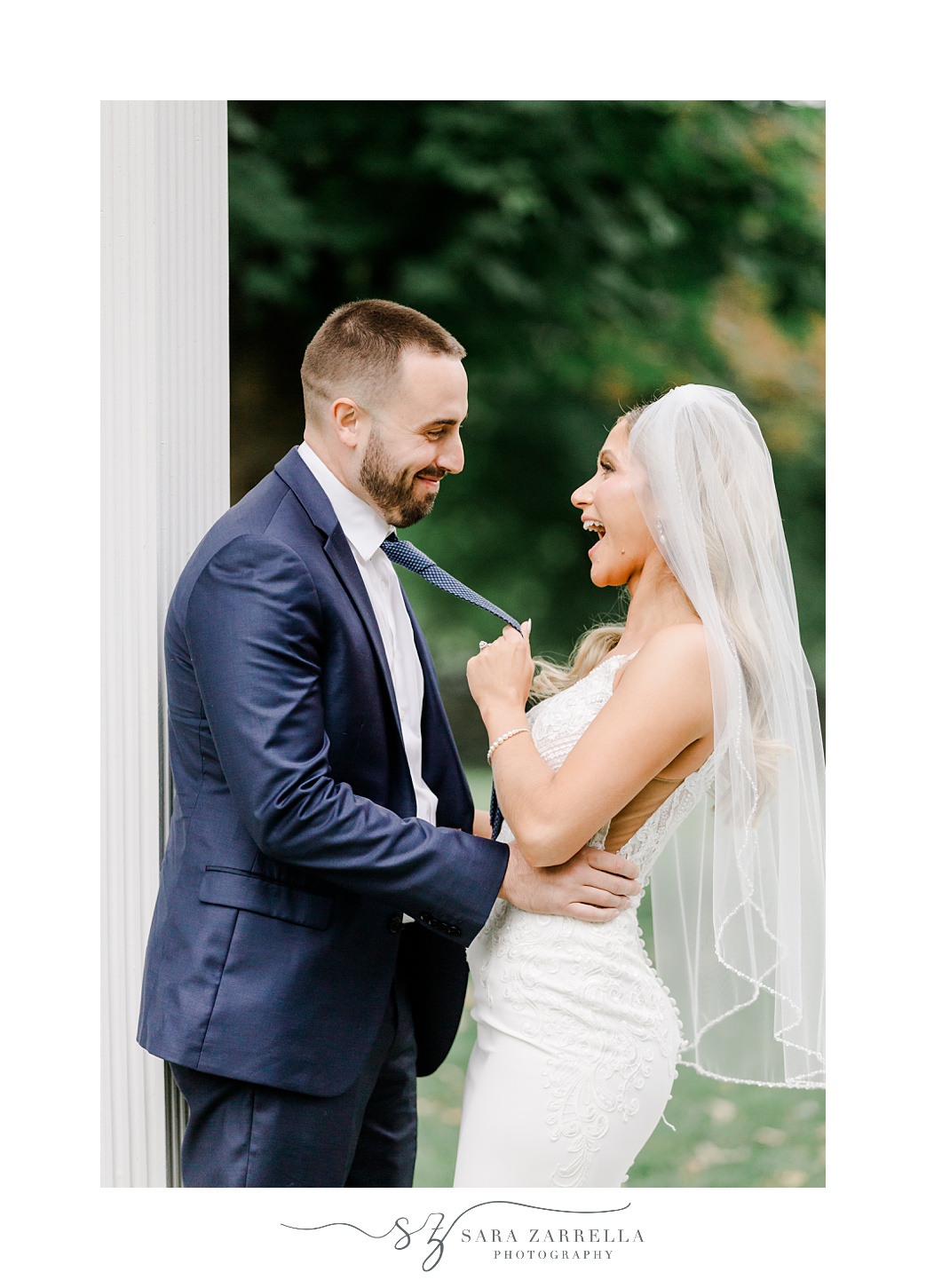 groom makes bride laugh while holding his tie 