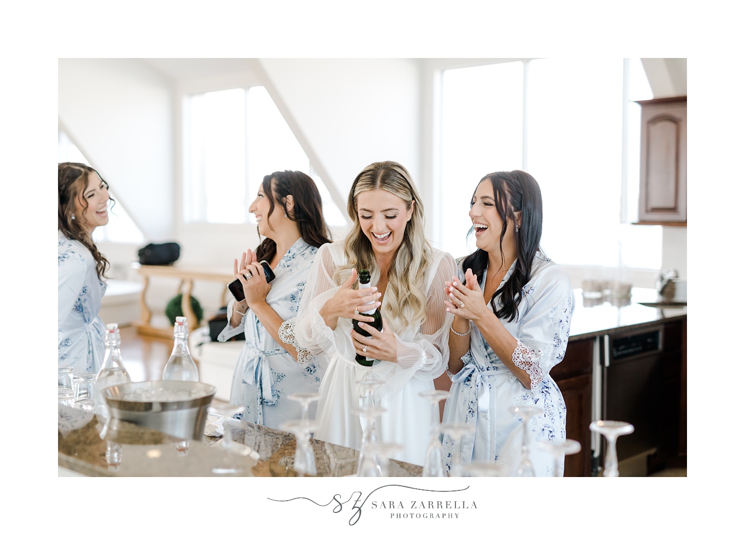 bride laughs with bridesmaids in blue robes with champagne 