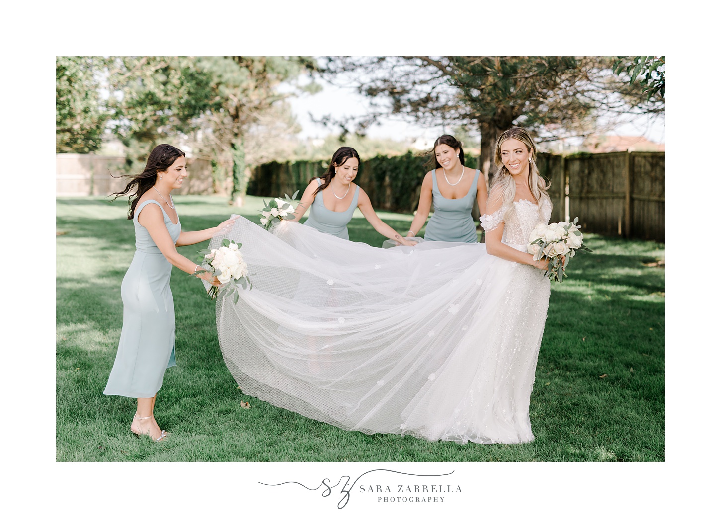 three bridesmaids in blue dresses help hold out bride's wedding dress skirt 