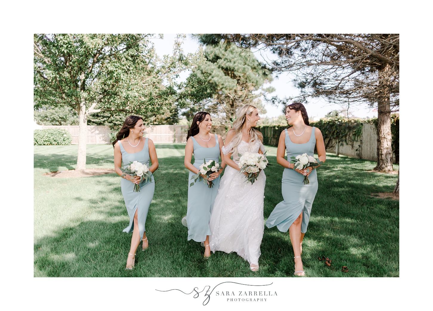 bride walks with three bridesmaids in blue dresses on lawn at Belle Mer Island House