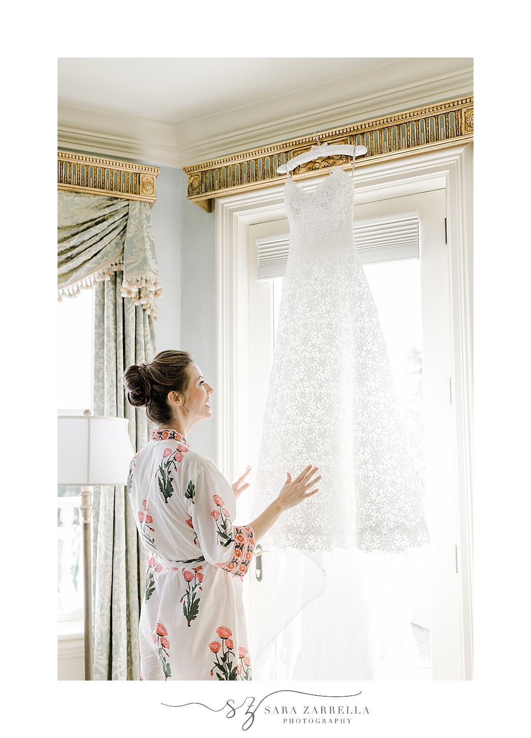 bride looks at dress hanging in window of the bridal suite at the Chanler