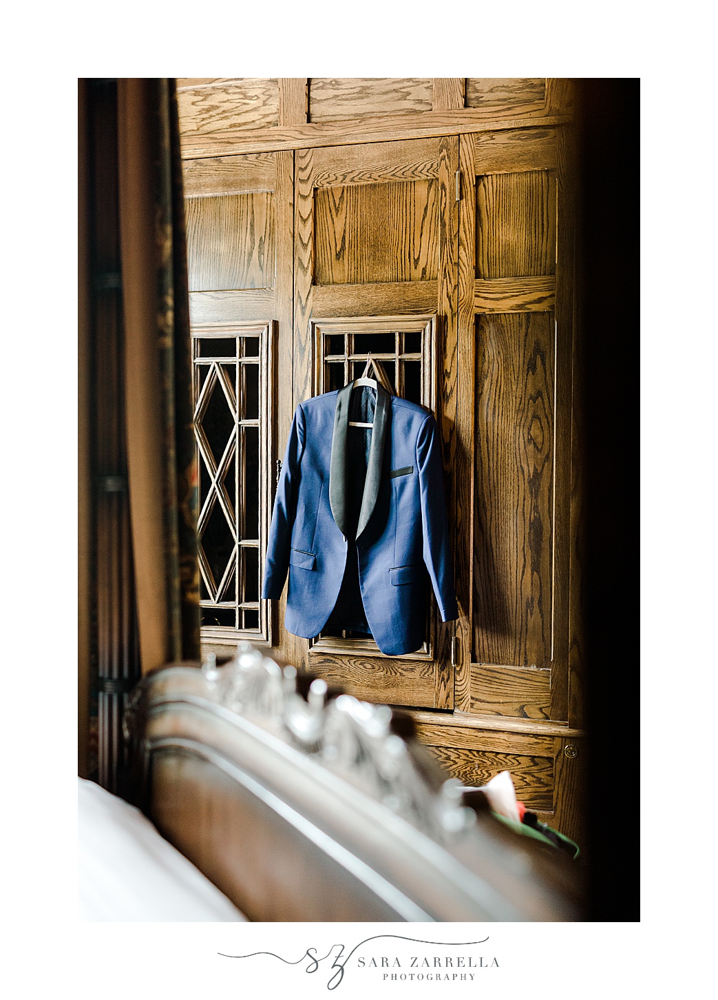 groom's blue jacket with black lapels hangs on wooden door inside the Chanler