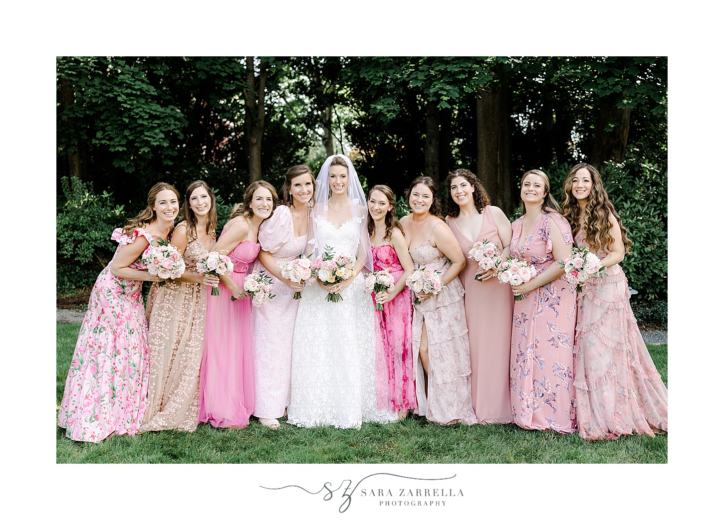 bride stands with bridesmaids in mismatch pink gowns on lawn at the Chanler